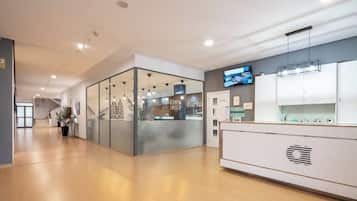 A modern reception area with a glass partition, a reception desk, and a mounted television.