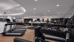 Ein modernes Fitnessstudio mit mehreren Laufbändern, Kraftgeräten und einer Spiegelwand.