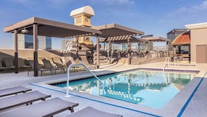 Ein Poolbereich auf dem Dach mit Liegestühlen, einem Pool und einer überdachten Sitzgelegenheit.