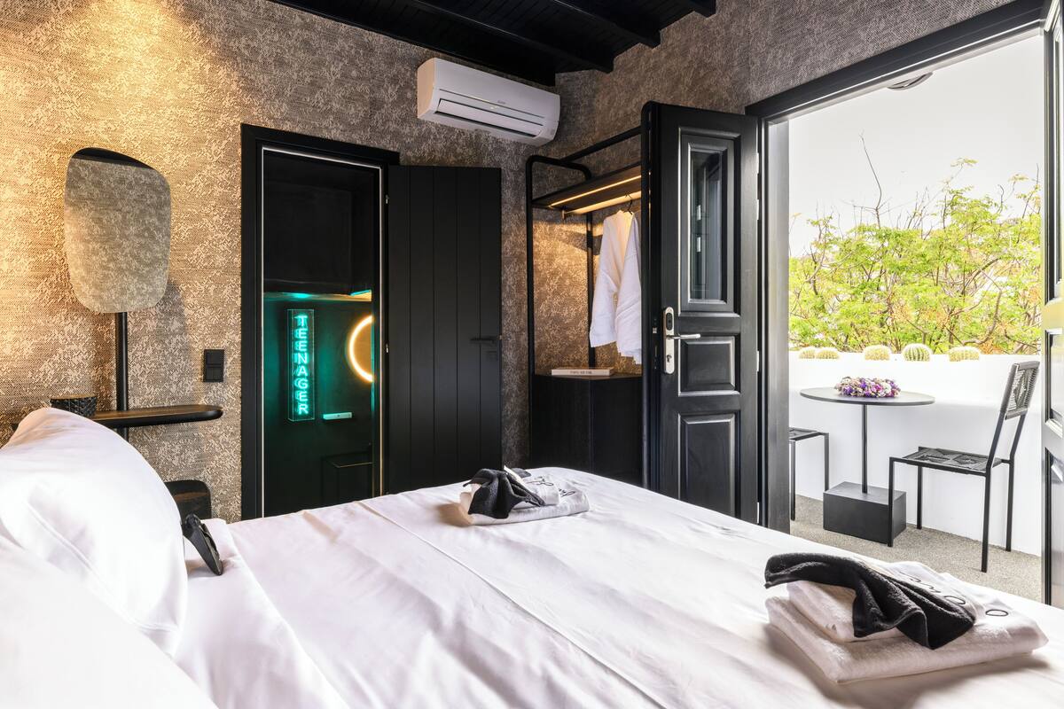Ein Hotelzimmer mit Bett, Kleiderschrank, Spiegel und Blick nach außen.