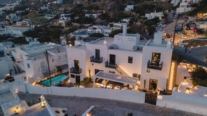Un bâtiment blanc doté d’une piscine et d’un espace extérieur aménagé, situé dans un quartier résidentiel vallonné.