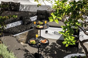 A dining area with a sofa and two tables set with meals and drinks.