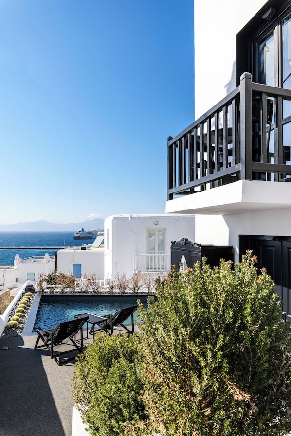 A modern building with a rooftop pool, outdoor seating, and a view of the sea.