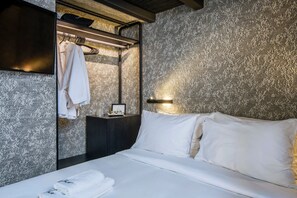 A hotel room with a bed, a nightstand, a mirror, and a wall with a textured pattern.