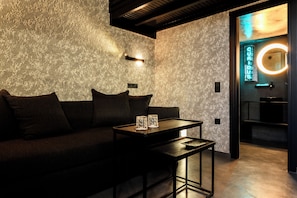 Een modern interieur met een structuurwand, een donkere bank en een tafel met twee kaarsen.
