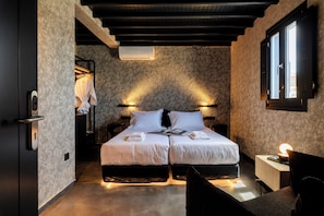 Een moderne slaapkamer met twee bedden, een nachtkastje, een leeslamp en een raam met gordijnen.