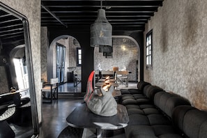 Een modern interieur met een donkere, industriële uitstraling, met een zithoek met een bank en een tafel waarop een beeldhouwwerk staat.