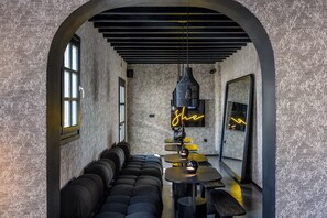 Un intérieur moderne avec un mur à l’aspect pierre, un plafond voûté noir, un néon et un espace salon.