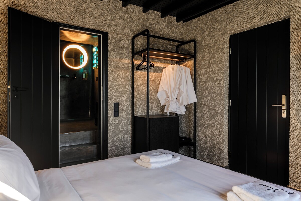 A modern hotel room with a bed, a built-in wardrobe, and a circular light fixture.