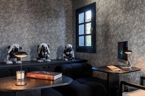 Quarto moderno com parede texturizada, uma janela, uma escrivaninha com um computador, um livro e três estátuas de cães.