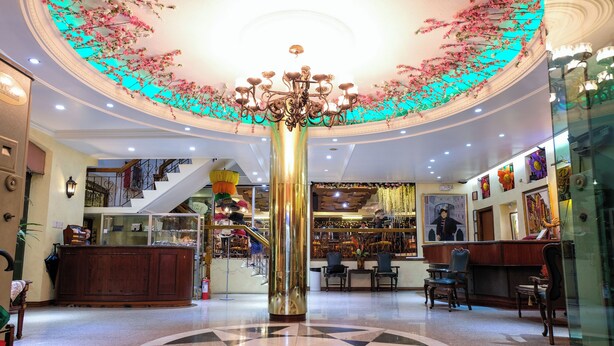 A lobby with a central chandelier, a reception desk, and a staircase leading to upper floors. - PATIO RIZAL HOTEL (Lucban)