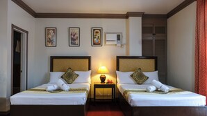 A hotel room with two beds, a nightstand with a lamp, and three framed artworks on the wall. - PATIO RIZAL HOTEL (Lucban)