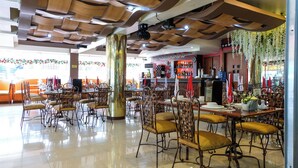 A spacious restaurant with high ceilings, wooden paneling, and a variety of seating arrangements including tables and chairs. - PATIO RIZAL HOTEL (Lucban)