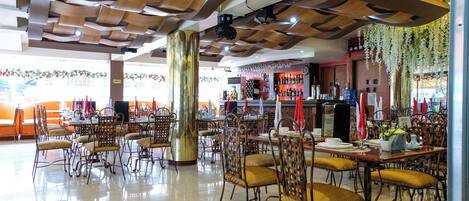 Un restaurante espacioso con techos altos, paneles de madera y diferentes opciones de asientos, incluyendo mesas y sillas.