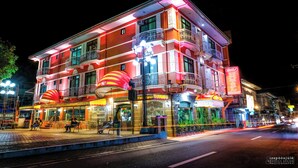 A brightly lit multi-story building with balconies and a ground-level restaurant. - PATIO RIZAL HOTEL (Lucban)