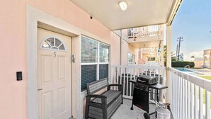 A covered porch with a bench, a grill, and a water heater.