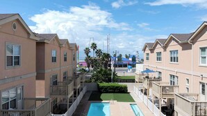 A residential building with multiple balconies, a swimming pool, and a view of the ocean.