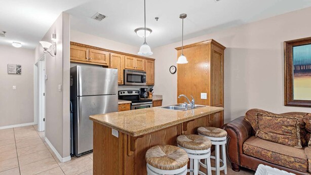 A modern kitchen with wooden cabinets, stainless steel appliances, and a central island with stools.