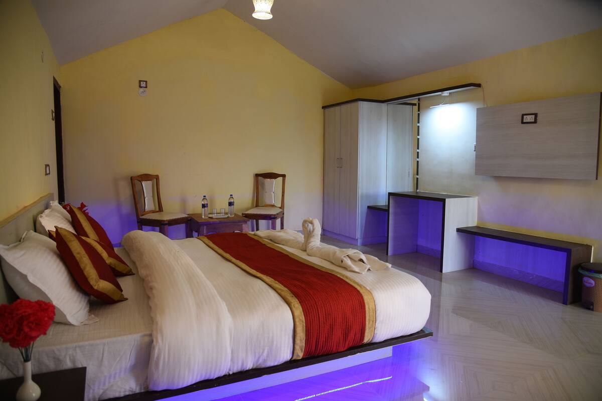 Una habitación de hotel con cama, mesitas de noche, escritorio, espejo y armario.