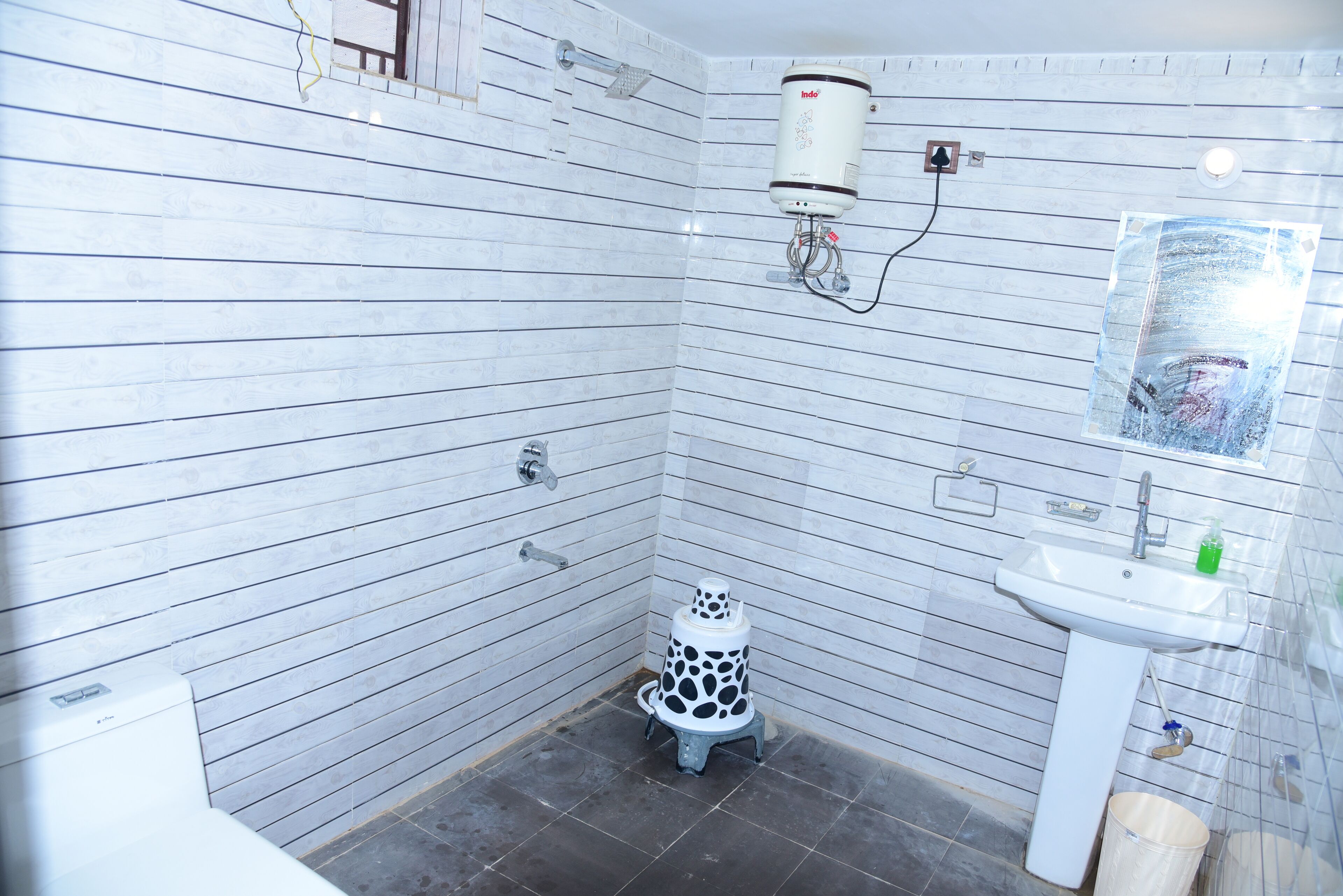 A small bathroom with white tiled walls, a white sink, and a toilet with a unique design.