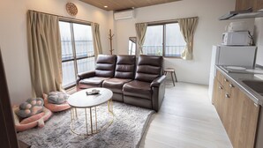A modern living room with a sofa, a small round table, and pet beds. - sun seinibannkan 201 (Osaka)