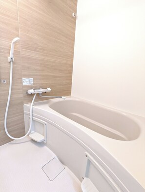 Een moderne badkamer met een badkuip, een handdouche en een bedieningspaneel.