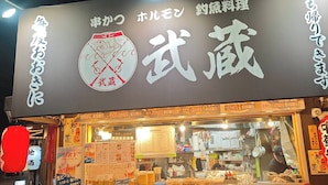 A Japanese restaurant with a signboard, menu, and a fan outside. - sun seinibannkan 201 (Osaka)