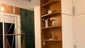 A room with a hanging chair, a tall bookshelf, and a green wall. - Apartments in the Heart of Copacabana (Rio de Janeiro)