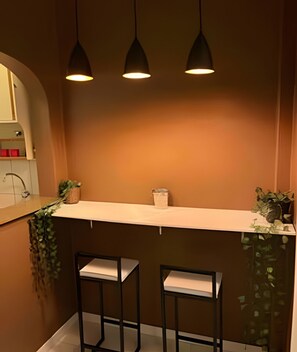 A kitchen with a white countertop, two black bar stools, and three pendant lights. - Apartments in the Heart of Copacabana (Rio de Janeiro)