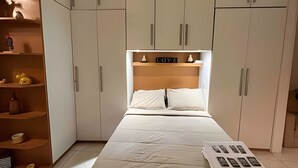 A bedroom with a bed, a nightstand, a shelf with decorative items, and a wardrobe with a 'LOVE' sign on the headboard. - Apartments in the Heart of Copacabana (Rio de Janeiro)