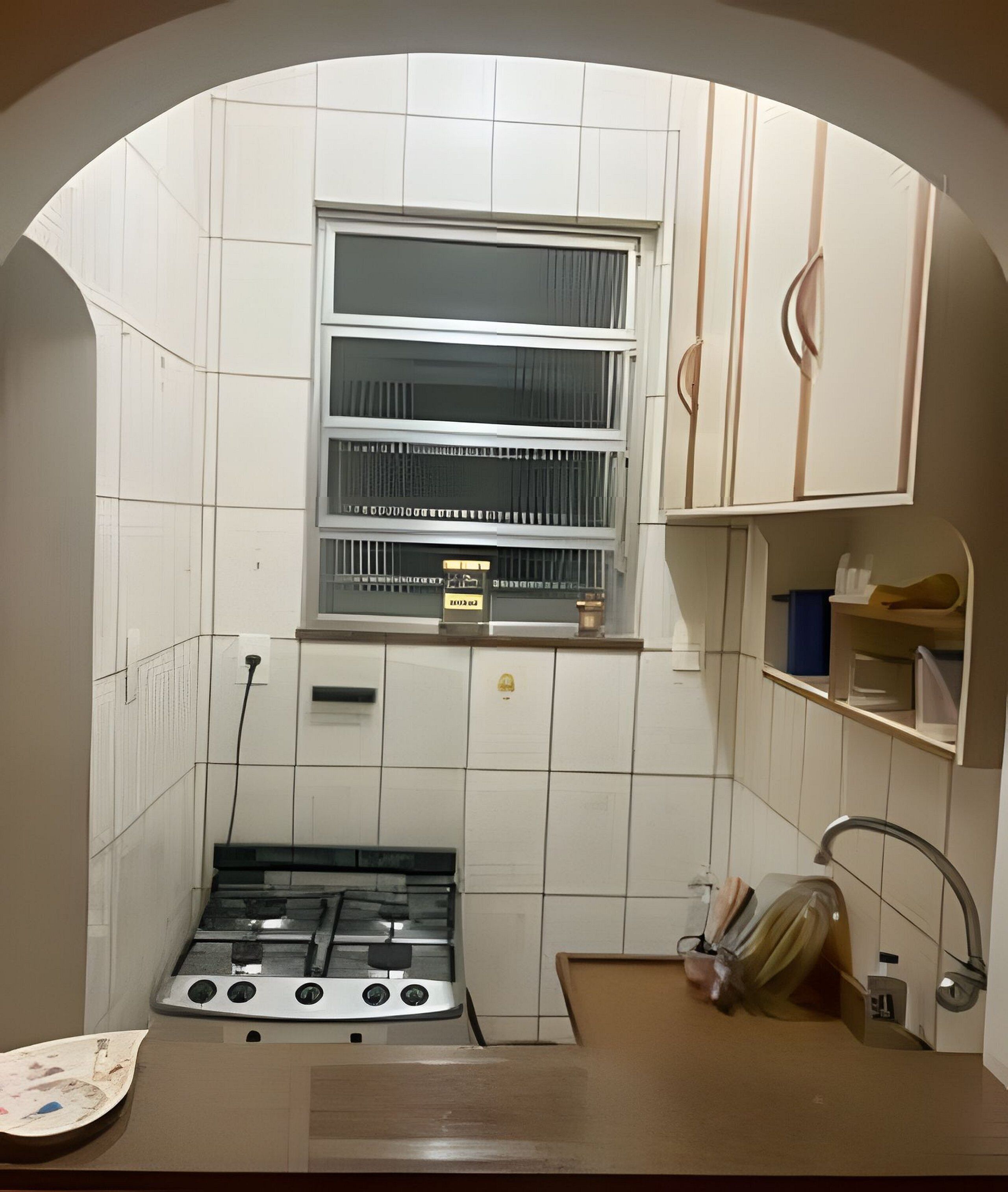 A compact kitchen with a gas stove, a window with blinds, and a small shelf above the stove.