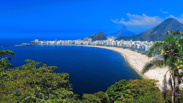 A coastal cityscape with a beach, buildings, and mountains. - Apartments in the Heart of Copacabana (Rio de Janeiro)
