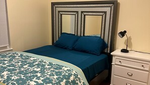 A bedroom with a bed, a nightstand, and a dresser. - NWK 457  ROOM 112-B (Newark)