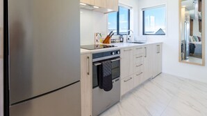 Une cuisine moderne dotée d’appareils électroménagers en acier inoxydable, de meubles de rangement en bois clair et d’une grande fenêtre qui laisse entrer la lumière naturelle.
