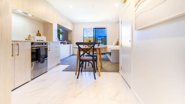 Una cocina moderna con comedor, que incluye un horno empotrado, una mesa con sillas y vistas al exterior a través de un ventanal grande.