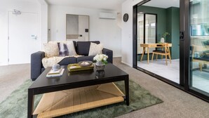 Ein modernes Wohnzimmer mit einem dunklen Sofa, einem Couchtisch und einem Essbereich mit einem Holztisch und Stühlen.
