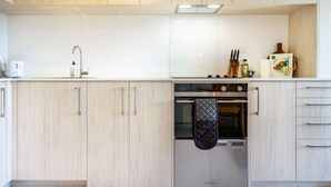 Et moderne køkken med lyse træskabe, en stålfarvet ovn og en indbygget opvaskemaskine.