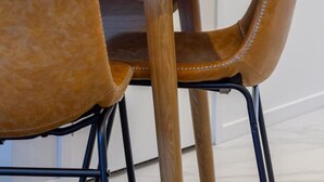 Una mesa de madera con dos sillas, una con textura similar al pelaje y la otra con apariencia de cuero.