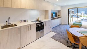 Una cocina moderna con horno integrado, un lavamanos y una zona de comedor con mesa y sillas.