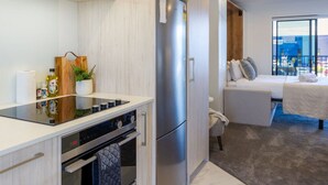 Een moderne keuken met een roestvrijstalen koelkast, een inbouwoven en een aanrecht met een waterkoker en een plant.