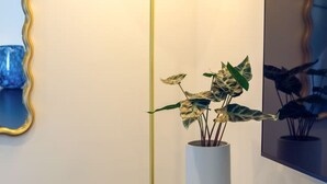 Een moderne kamer met een vloerlamp, een potplant, een spiegel en een abstract kunstwerk aan de muur.