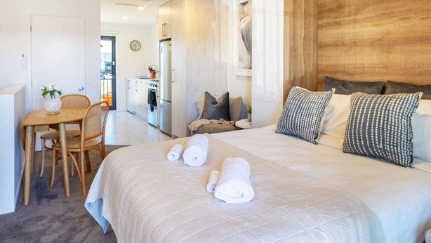 Een hotelkamer met een bed, een bureau en een kitchenette.
