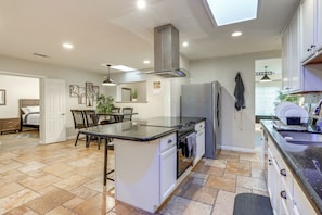 Enjoy meals in the kitchen with an oven and stainless steel refrigerator, surrounded by a skylight and large window.