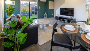 A modern living room with a sofa, a coffee table, and a dining area with a table set for two.