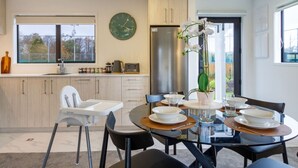 A modern kitchen with a dining area, a high chair, and a large window.
