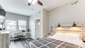 Un dormitorio con cama, mesitas de noche, escritorio y una silla.