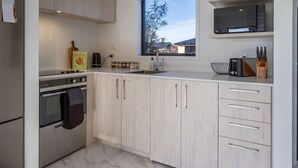 Una cocina moderna con armarios blancos, horno empotrado y ventana con vistas al exterior.