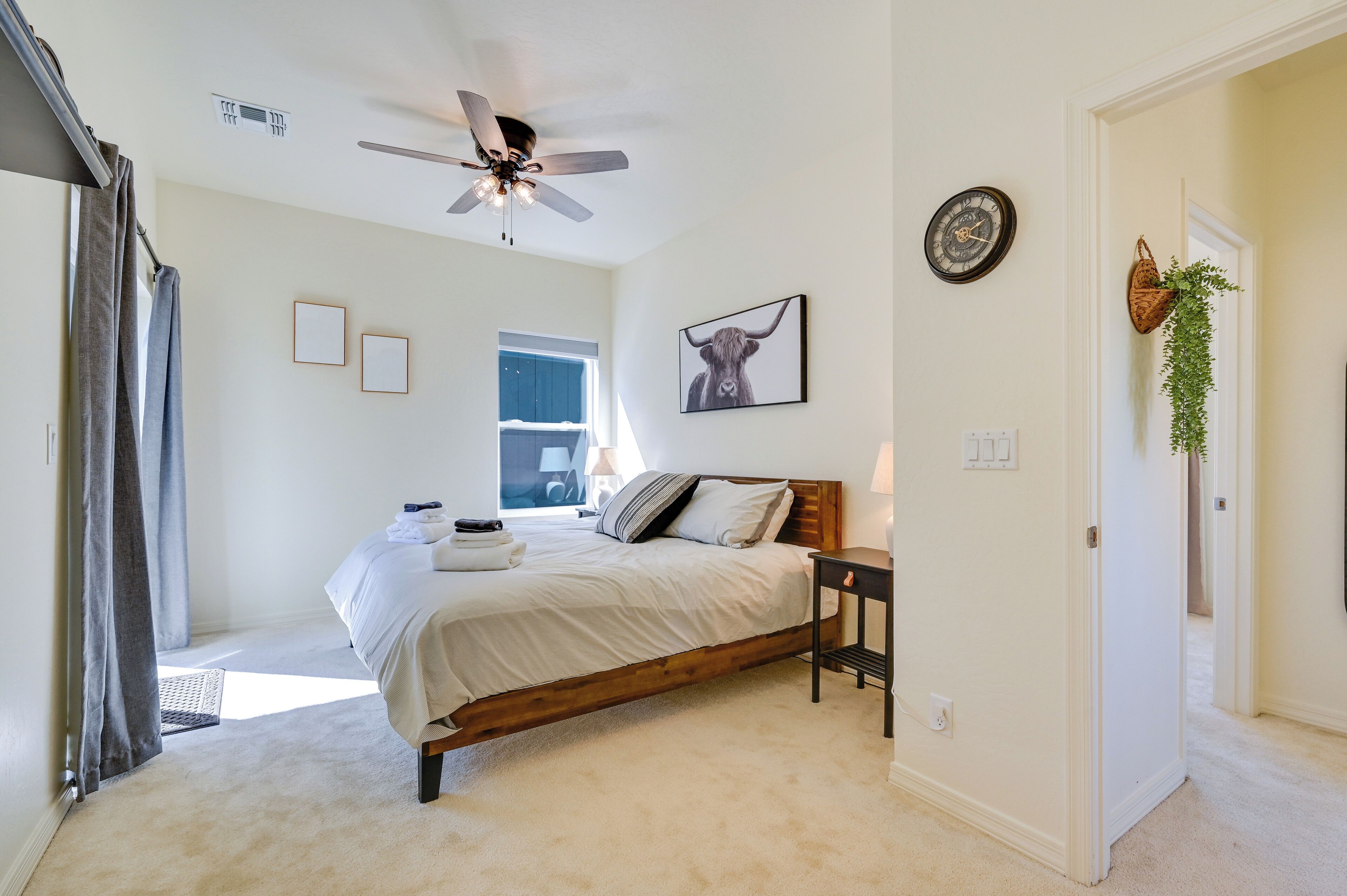 Un dormitorio con cama, ventilador de techo, ventana y puerta.