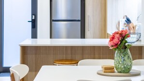A modern kitchen with a stainless steel refrigerator, a white countertop, and a dining area with a white table and chairs. - Cozy and Chic in Central Christchurch (Christchurch)
