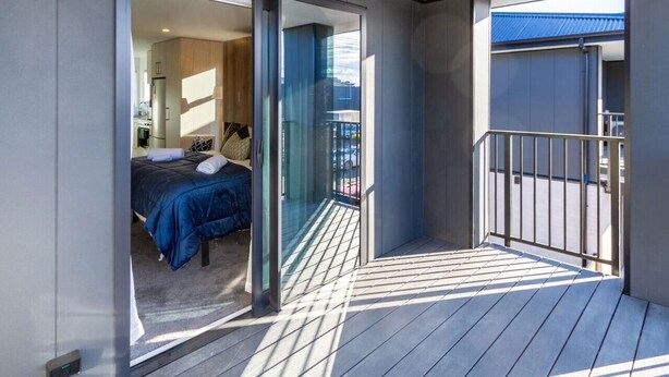 Une chambre d’hôtel moderne avec balcon, un lit et une vue sur la ville.